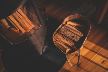 Top-down view of a cozy interior with a black wood-burning stove and a wicker basket full of...