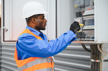 Joyful african american electrician mounting electric switchboard outdoors