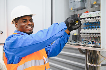 A male african american electrician works in a switchboard