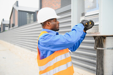 A male african american electrician works in a switchboard