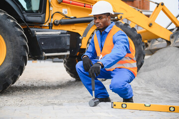 African american master in gloves lays paving stones in layers. Garden brick pathway paving by...