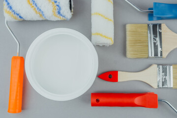 Set of paint tools with colorful rollers, brushes and bucket of white paint for DIY renovation and...