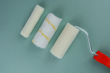 Three paint rollers on green background for painting variety and DIY concept
