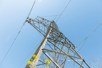 A tall power tower with wires and a blue sky in the background