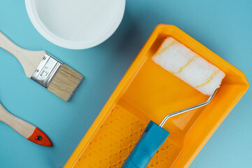 Close up of paintbrush and roller tray on cyan background for decoration tools and home design...