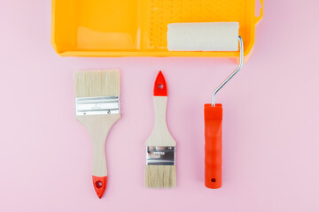 Painting set with tray, roller and brushes on pink background for DIY tools and interior work...
