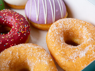 Donuts with different colorful icing designs arranged in a box.