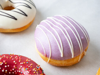 Donuts with different colorful icing designs on a white background.