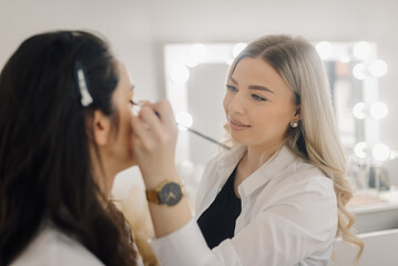 Makeup artist applying makeup on client's eyelid in beauty salon