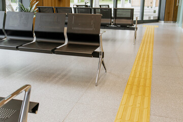Empty metal bench seats in a public waiting area, minimalistic interior, polished floor, and wooden...