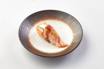 Grilled salmon sushi topped with creamy avocado, fish roe, and drizzle of sauce, served on textured...