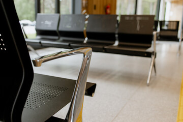Empty metal bench seats in a public waiting area, minimalistic interior, polished floor, and wooden...