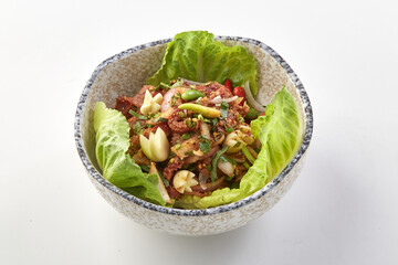 Bowl of spicy raw chopped beef salad garnished with fresh herbs, garlic, and vegetables, served on bed of crisp lettuce leaves in ceramic bowl, showcasing vibrant colors and textures