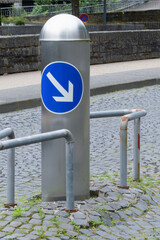 A metal pole in the middle of the roadway, enclosed by a steel frame for safety and bypassing