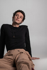 Vertical studio portrait of curly haired boy lying on the floor
