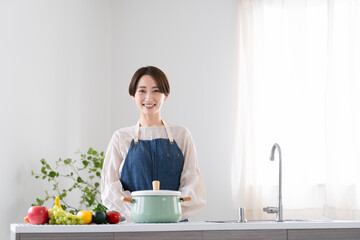 エプロン姿で料理する若い女性　ライフスタイルイメージ