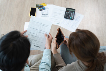 Stressed and headache asian couple with large bills or invoices no money to pay to expenses and...