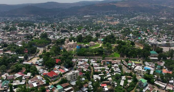 Fasil Ghebbi - Royal Enclosure In Gondar, Ethiopia - HIstoric Castle And Lush Garden Surrounded By City Buildings. aerial approach