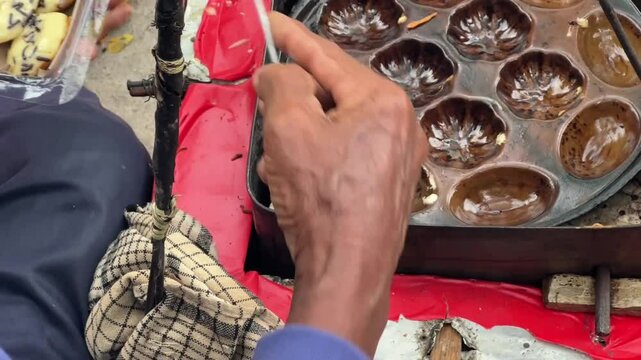Street vendor preparing kue cubit &mdash; a popular Indonesian mini pancake snack cooked fresh on the roadside, loved for its soft texture and nostalgic flavor. Karet, Indonesia - June 25, 2025
