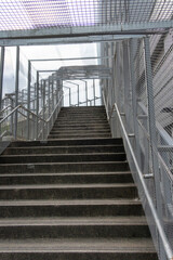 A photo of a concrete staircase leading to an overhead pedestrian walkway.