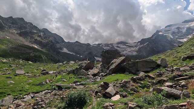 Scenic Alpine Landscape with Boulders and Flowing Stream Beneath Glacial Peaks Near Rifugio Pastore in Monte Rosa, Alagna Valsesia