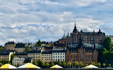 View of Historic buildings of Södermalm waterfront, Stockholm, Sweden with summer umbrellas in the foreground at Munkbrohamnen.