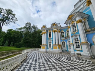 Blue and white building with a large balcony. The building has a lot of windows and a lot of trees...