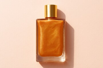 A bottle of shimmering golden oil with a gold cap on a peach surface