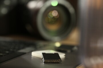 SD memory cards, holder, laptop and photo camera on table, closeup