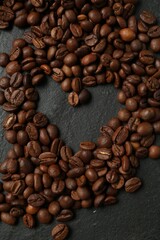Heart shaped of coffee beans on black table, flat lay