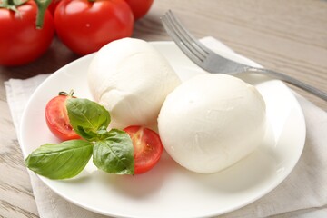 Tasty mozzarella cheese balls, tomatoes and basil on table, closeup