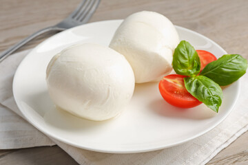 Tasty mozzarella cheese balls, tomato and basil on table, closeup