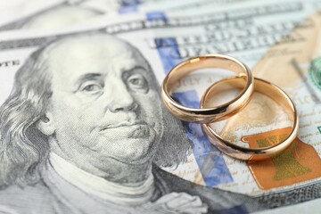 Two gold wedding rings on dollar banknotes, closeup