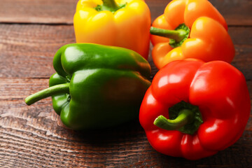 Fresh colorful bell peppers on wooden table, closeup