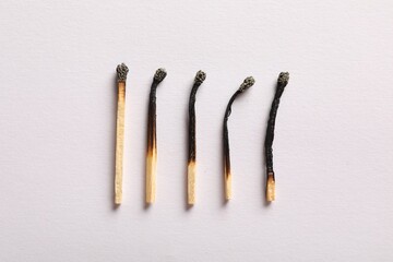 Burnt matches on light grey background, flat lay