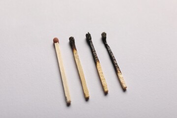 Burnt and whole matches on grey background, closeup