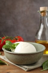 Tasty mozzarella balls, tomatoes, oil and basil on wooden table, closeup