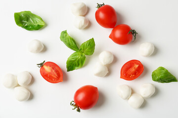 Tasty mozzarella balls, tomatoes and basil on white background, flat lay