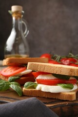Tasty sandwiches with mozzarella cheese, tomatoes and basil on table, closeup