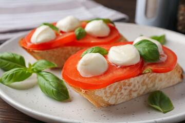 Tasty sandwiches with mozzarella cheese, tomatoes and basil on table, closeup