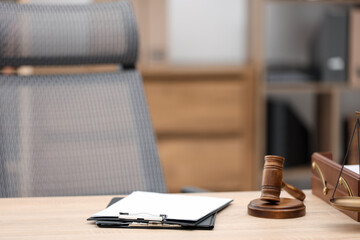 Judge's gavel, clipboards and scales on wooden table in office