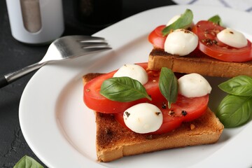 Tasty sandwiches with mozzarella cheese, tomatoes and basil on dark textured table, closeup