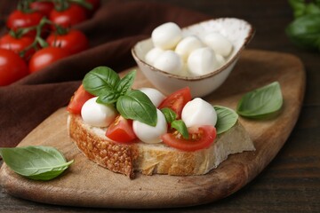 Tasty sandwich with mozzarella cheese, tomatoes and basil on wooden table, closeup