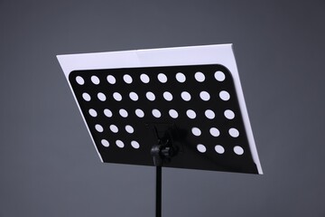 Note stand with music sheets on grey background, closeup