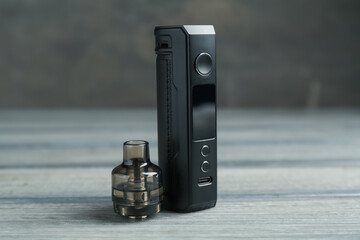 Electronic smoking device and cartridge on wooden table against grey background, closeup
