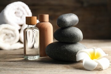 Composition with cosmetic products and spa stones on wooden table, closeup