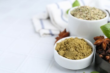 Different aromatic spices on white tiled table, closeup. Space for text