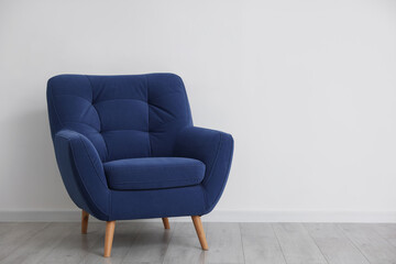 Comfortable blue armchair near white wall indoors, space for text