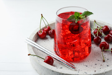 Tasty cherry soda with ice cubes, mint and berries on white wooden table, closeup. Space for text