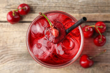 Tasty cherry soda with ice cubes and berries on wooden table, flat lay